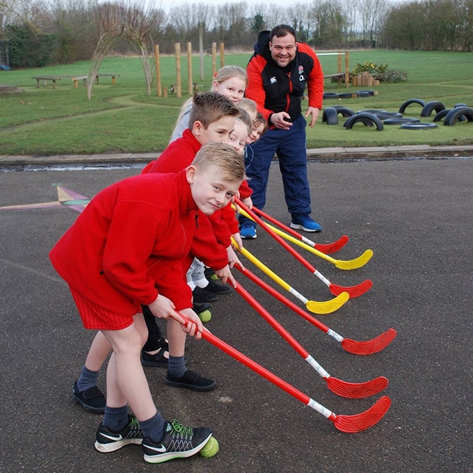 A row of pupils holding hockey sticks