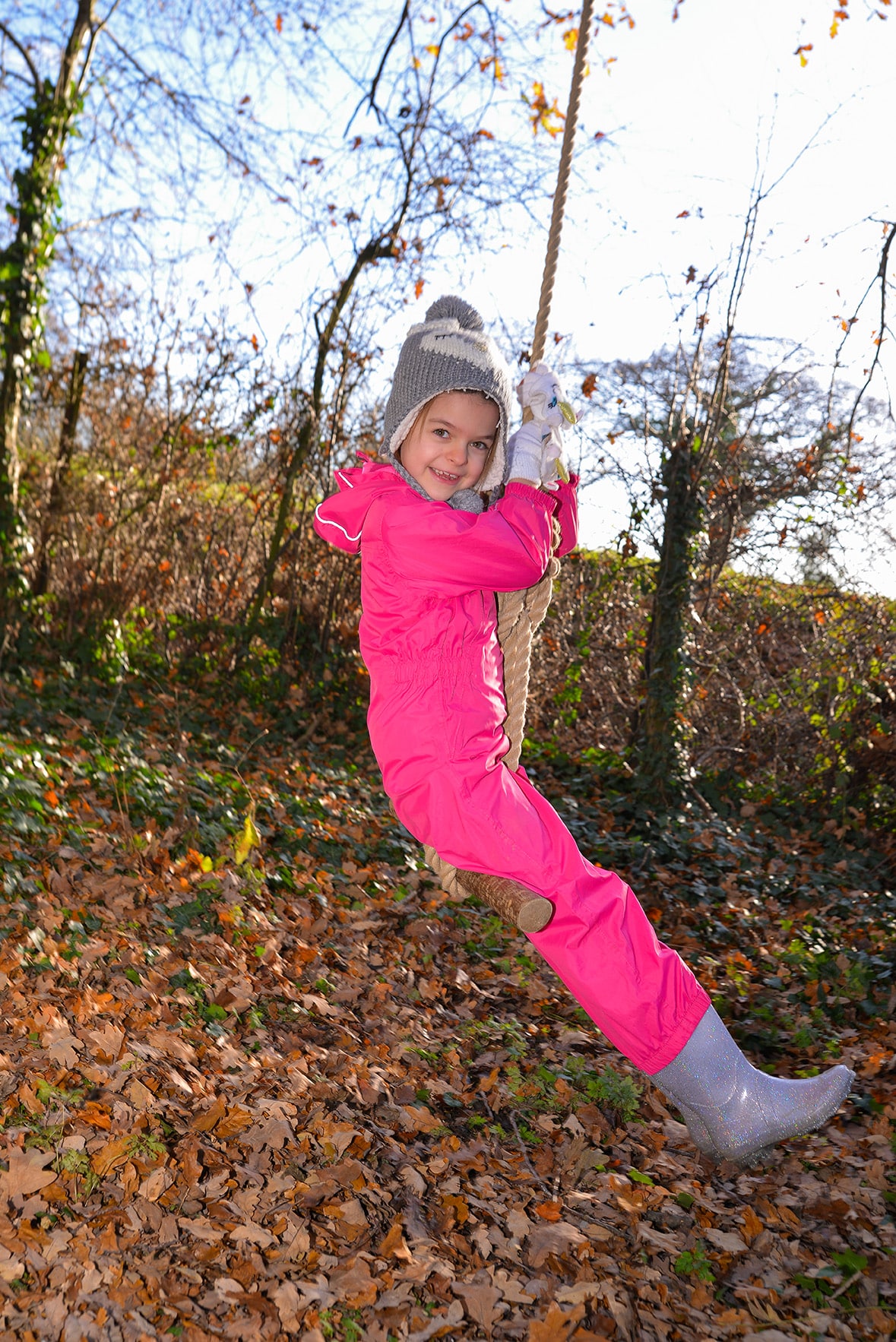 A girl swinging on a rope swing during forest school