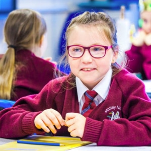 Student from Mistley Normal Primary School smiling at desk in classroom
