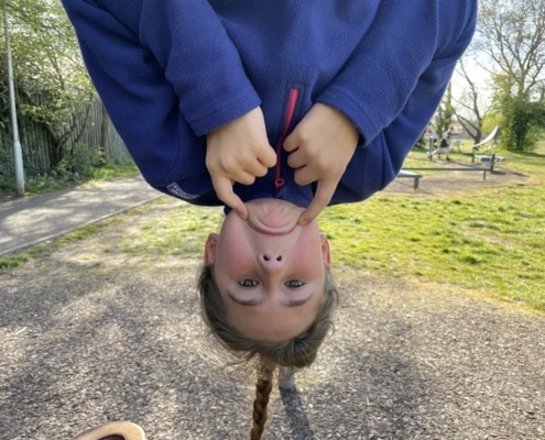 Pupil at St Margaret's enjoying Make Me Smile Day whilst dangling upside down