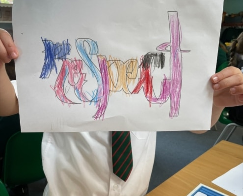 Pupil holding up paper with Respect written on it in multicolour