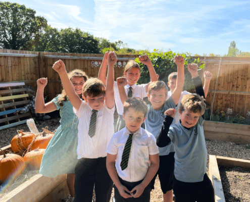 Children at St Andrew's Weeley celebrating winning an Anglia in Bloom award in their school allotment.